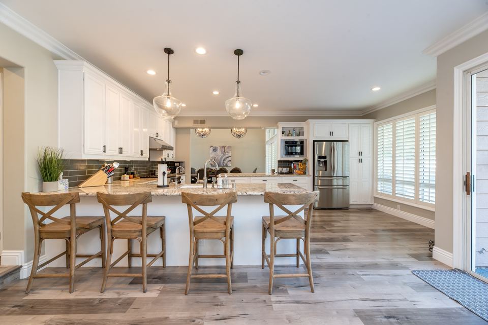 Kitchen with a stainless French-door refrigerator beside white cabinets and a peninsula sink