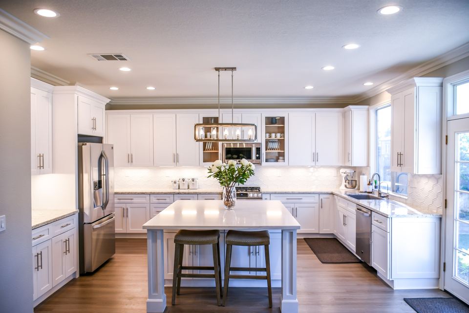 Bright white kitchen with a large island, pendant lights and a stainless range